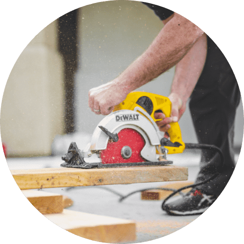 an image of a man using an electric saw to cut through wood
